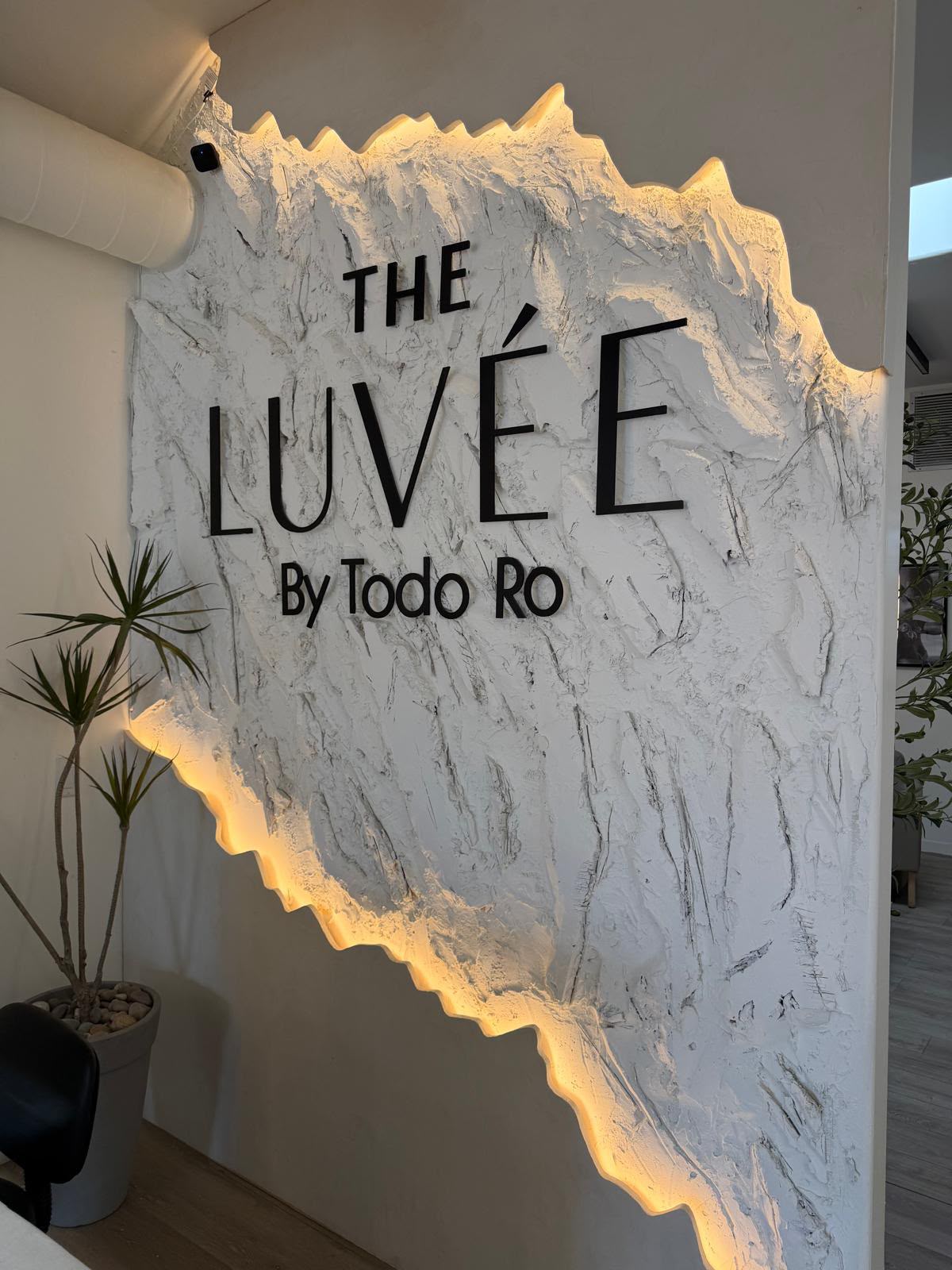 The Luvée · By Todo Ro. Torn-marble relief, backlit warm.